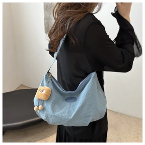 Detailed view of light blue nylon dumpling bag with cute plush toast pendant and gold buckle