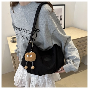 Detail of black canvas tote bag with bread plush charm and fashion side label
