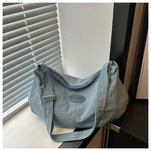 Detail of blue nylon tote bag showing pleated texture and adjustable metal strap buckle