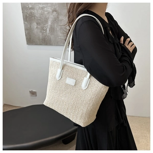 Detail of hand-woven straw tote bag with white leather trim and long shoulder straps