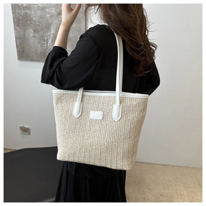 Detail of the woven straw tote bag with white faux leather trim and sturdy shoulder strap