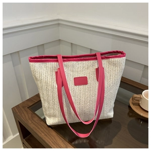 Detail of straw woven tote bag featuring bright magenta leather straps and trim texture