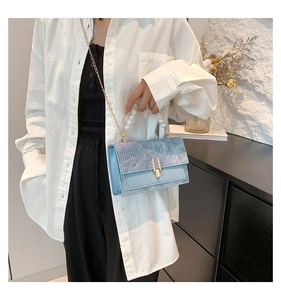 Détail du sac bandoulière tissé bleu clair avec poignée perle et chaîne dorée