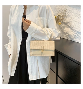 Détail du sac tissé crème avec poignée en perles et chaîne dorée porté par un mannequin