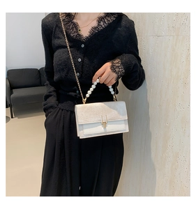 Gros plan du petit sac carré élégant avec texture tissée, poignée perle et chaîne