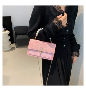 Détail du sac à bandoulière rose tissé avec boucle dorée, perles et chaîne fine