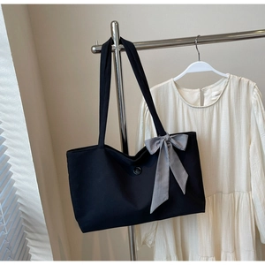 Detail of black canvas tote bag featuring a chic black and white checkered bow ornament