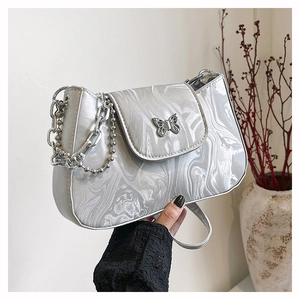 Detail of silver marble shoulder bag with metallic butterfly and chain handle