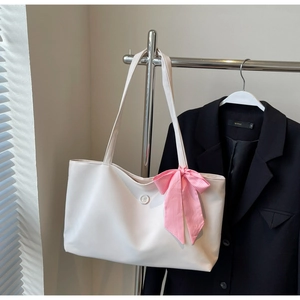 Detailed view of white faux leather tote bag with ribbon bow and round buckle detail