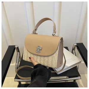 Detail of hand holding a straw and beige leather crossbody bag with silver twist lock