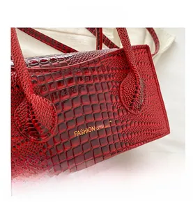 Close-up of red croc-effect leather handbag with gold Fashion & Bags logo engraving