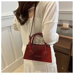 Detail of dark red crocodile pattern handbag showing elegant trapezoid shape and fine texture