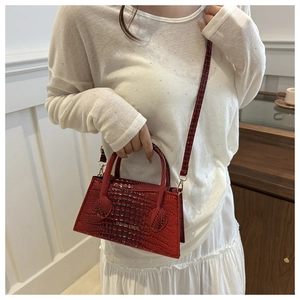 Detail of red crocodile texture handbag featuring fashion gold lettering and shoulder strap