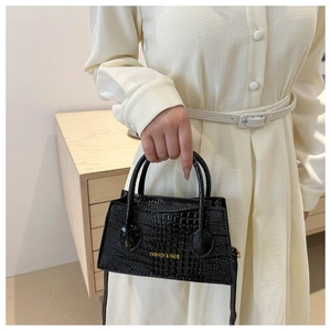 Close-up of black crocodile pattern faux leather handbag with gold fashion lettering