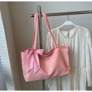 Pink fabric tote bag with a checkered bow detail hanging on a hanger for daily use