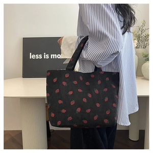 Détail du sac cabas en velours côtelé noir avec motifs fraises rouges et anse solide