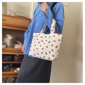 Détail macro du sac cabas en velours côtelé avec imprimé fraises sur tissu crème