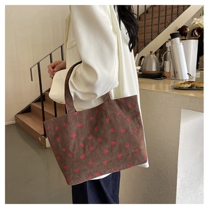 Détail du tissu en velours côtelé marron du cabas à motif fraises dans un café chic