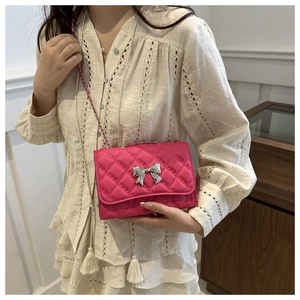 Macro detail of rose pink quilted leather bag with silver bow accent and chain strap