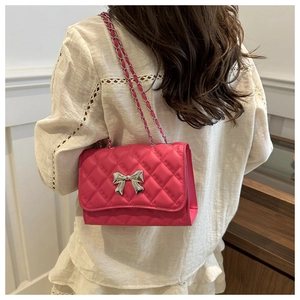 Close-up of hot pink quilted crossbody bag with silver bow clasp and chain strap