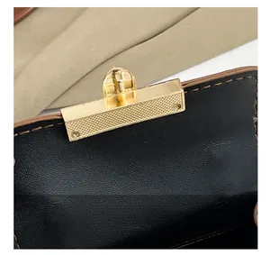 Dettaglio macro della chiusura dorata con texture a griglia su borsa in pelle nera