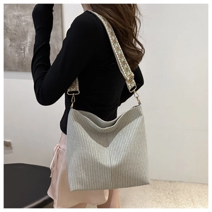 Detail of woven tote bag featuring an ethnic jacquard wide shoulder strap and metal hooks