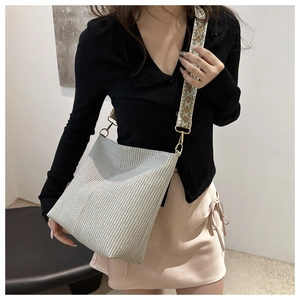 Vintage woven bucket bag with patterned wide strap shown on model in a minimalist room