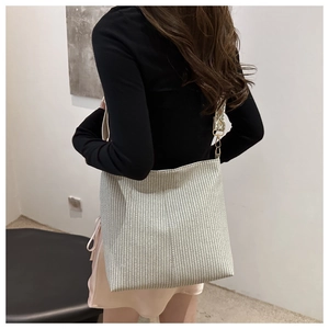 Rear view of a model wearing the large grey plaid woven tote bag with wide shoulder strap