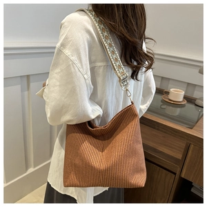 Detail of a brown woven tote bag featuring a vintage geometric jacquard wide strap