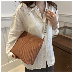 Detail of brown woven tote bag featuring a wide geometric pattern shoulder strap