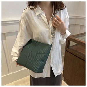 Detail of dark green woven crossbody bag with wide geometric pattern strap