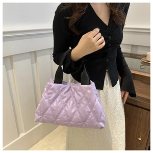 Detailed view of light purple quilted handbag with classic diamond stitching and black strap