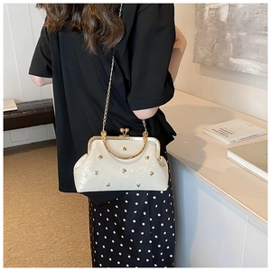 Détail du sac beige avec clous en cœur dorés et fermoir rétro en métal poli