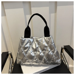 Close-up of silver quilted tote bag with metallic finish and black woven strap detail
