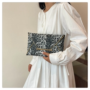 Detail of grey leopard print envelope clutch featuring elegant gold metal trim and buckle