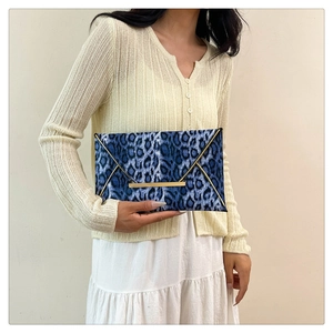 Blue leopard print envelope clutch bag with gold metal trim held by a female model