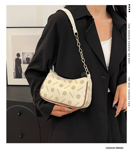 Detail of vintage monogram shoulder bag with gold chain strap on a black suit