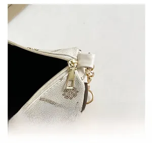 Detail of gold metal zipper and vintage floral print on beige leather shoulder bag