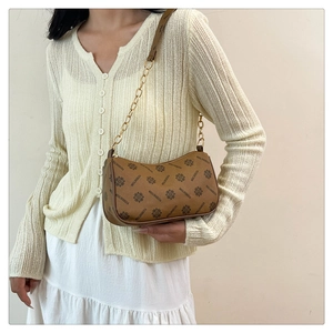 Close-up of brown vintage pattern underarm bag with gold chain and leather strap details