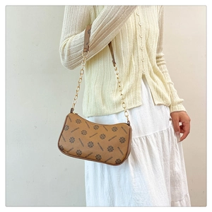Detail shot of the vintage monogram pattern and gold metal chain on the brown shoulder bag