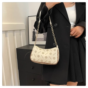 Detail of vintage monogram shoulder bag with gold chain strap on a black blazer