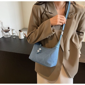 Détail du sac en denim bleu clair avec coutures en losange et breloques en perles blanches
