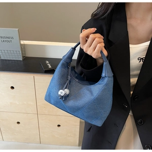 Détail du sac croissant en denim bleu avec surpiqûres losanges et zip perlé