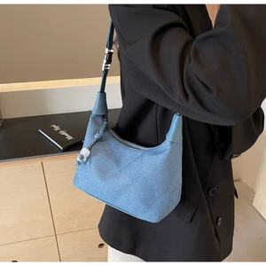 Détail macro du sac hobo en denim matelassé avec boucle argentée et surpiqûres bleu clair