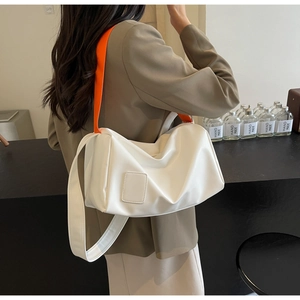 Minimalist white leather cylindrical bag with contrasting bright orange fabric strap