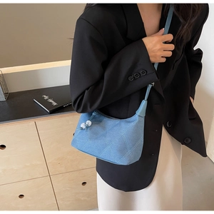 Sac à bandoulière en denim matelassé bleu clair porté par un mannequin en blazer