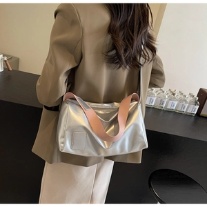 Detail view of silver cylindrical pillow bag featuring a wide pink shoulder strap on model