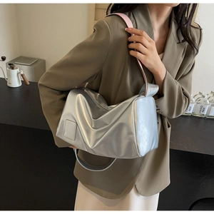 Detail of silver metallic cylinder bag with light pink strap on a brown suit jacket