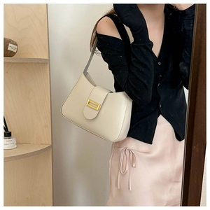 Chic cream leather underarm bag with gold buckle styled in an elegant outfit view