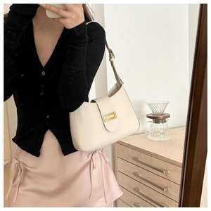 Detail of cream white leather shoulder bag with a gold metal clasp and adjustable strap